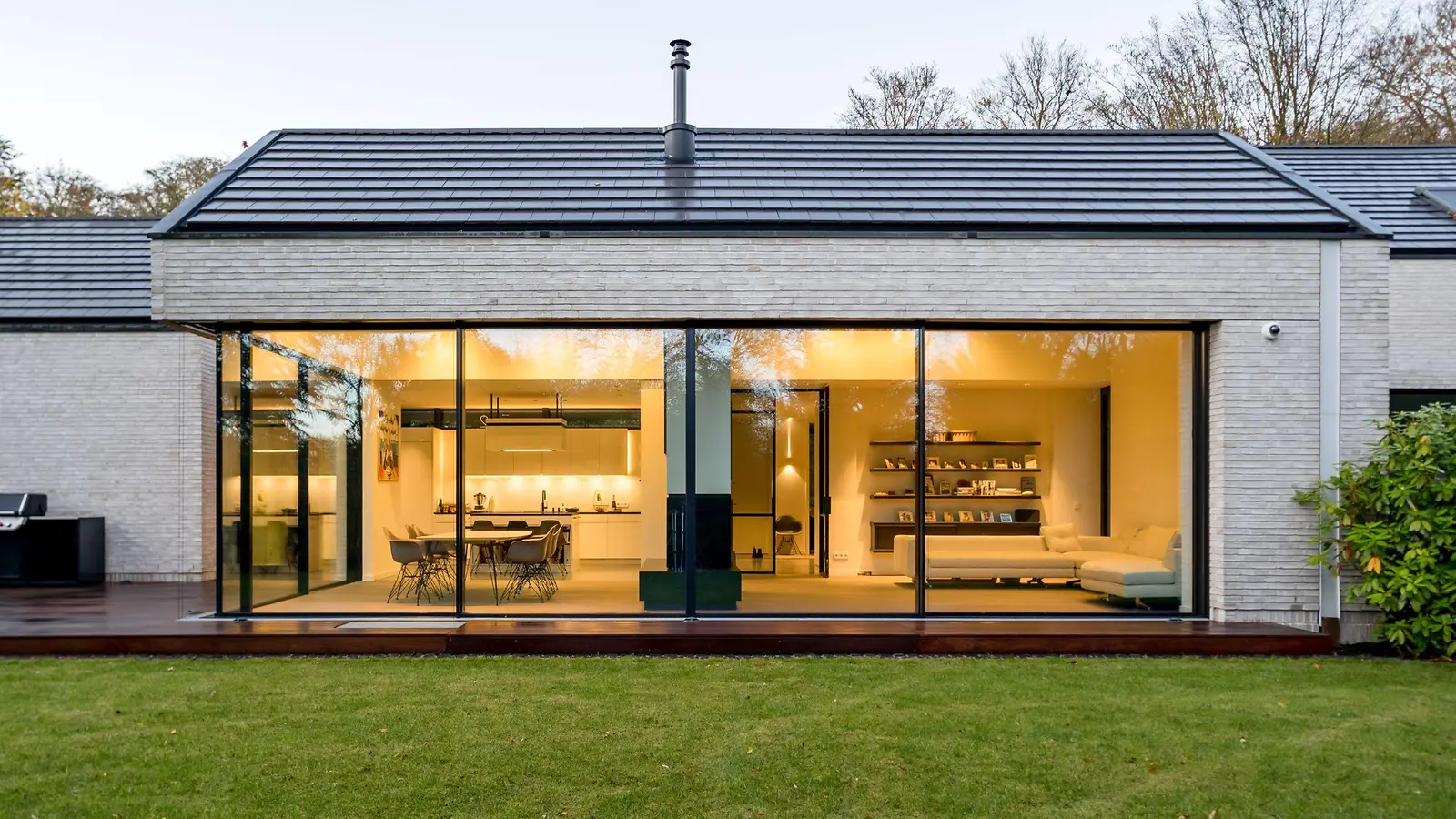 Modernes Haus mit rahmenloser Ganzglas-Eckverglasung aus Aluminium am Abend